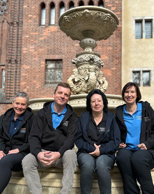 Spreequeem Team sitzend vor einem Brunnen in Berlin-Mitte